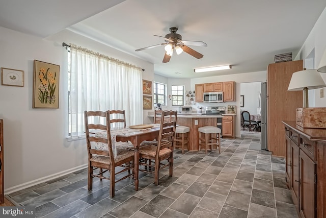 dining space with a ceiling fan and baseboards