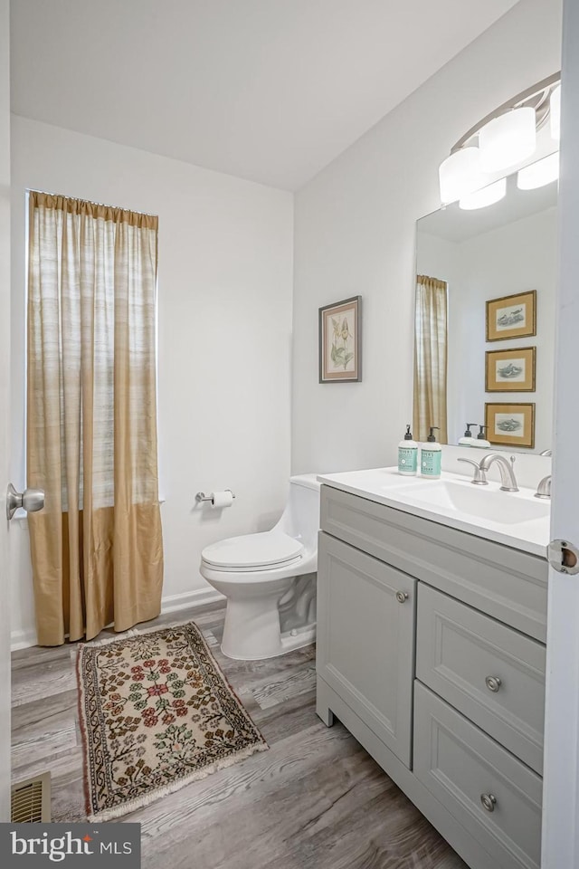 bathroom featuring toilet, vanity, visible vents, and wood finished floors
