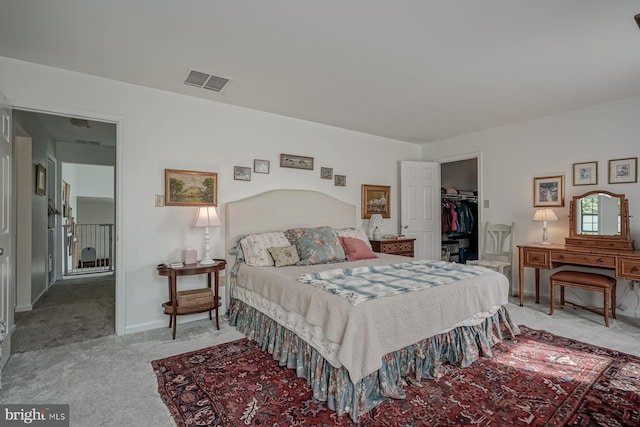 carpeted bedroom featuring a walk in closet, visible vents, and baseboards