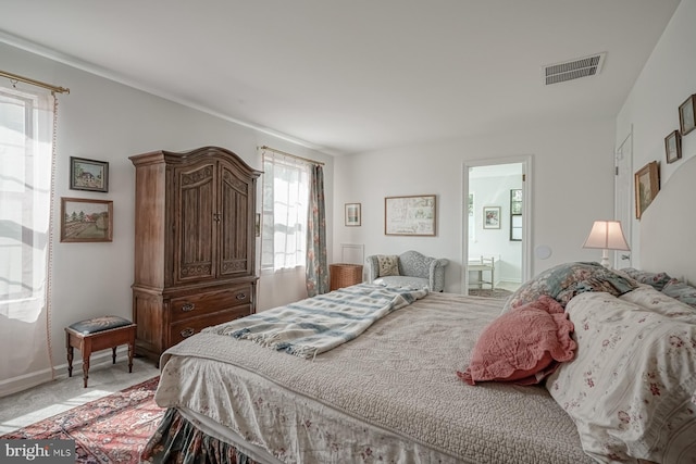 bedroom with connected bathroom, visible vents, light carpet, and baseboards