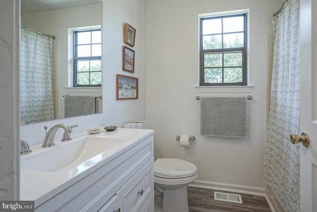 full bathroom with vanity, toilet, visible vents, baseboards, and wood finished floors