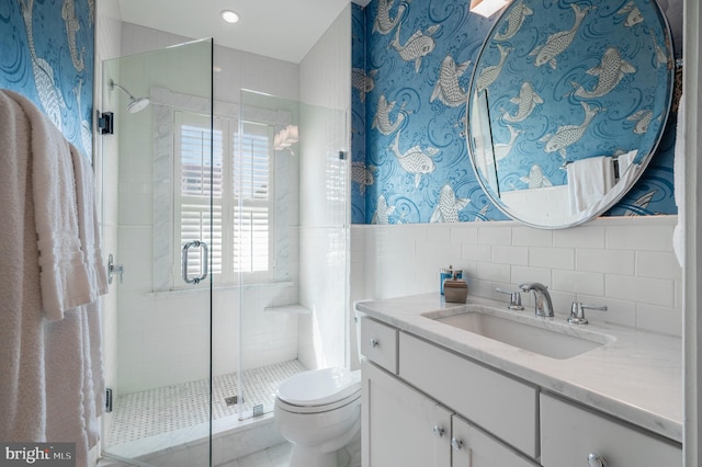 full bathroom with vanity, tile walls, a shower stall, and toilet