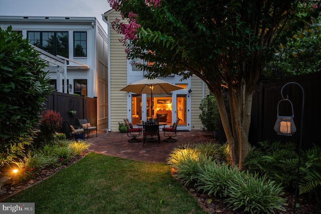 back of property featuring a lawn, a patio, and fence