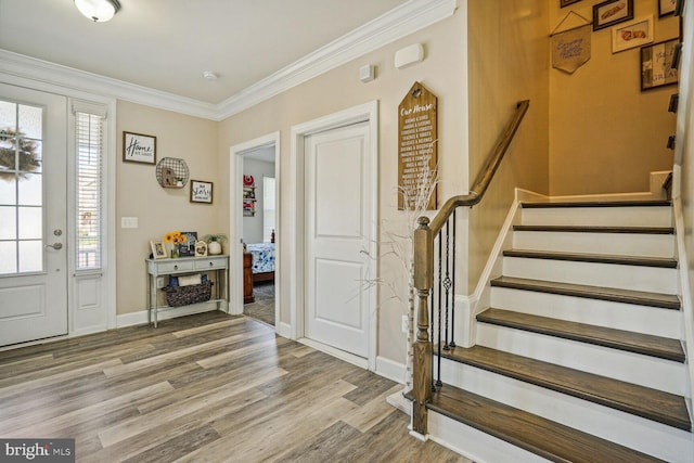 entryway with baseboards, ornamental molding, stairs, and wood finished floors