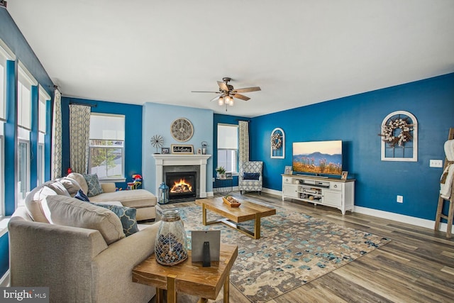 living area featuring plenty of natural light, baseboards, ceiling fan, and wood finished floors