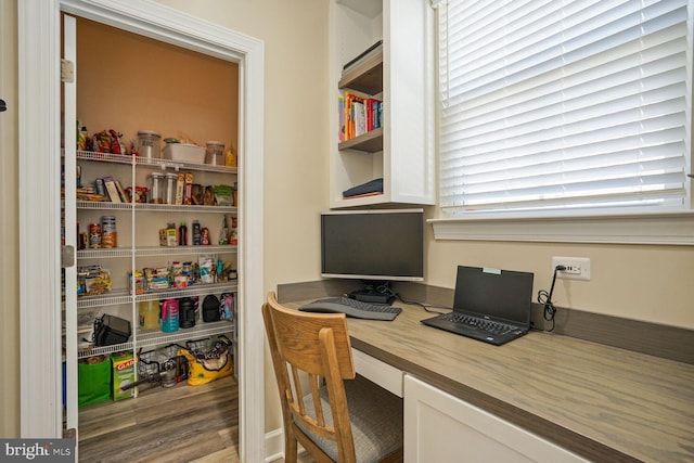 home office featuring built in desk and wood finished floors