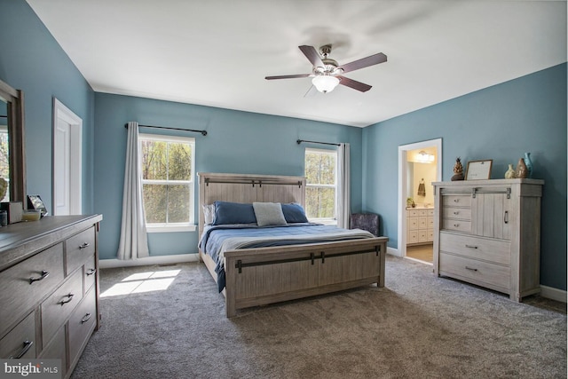 carpeted bedroom featuring baseboards, ceiling fan, ensuite bath, and multiple windows