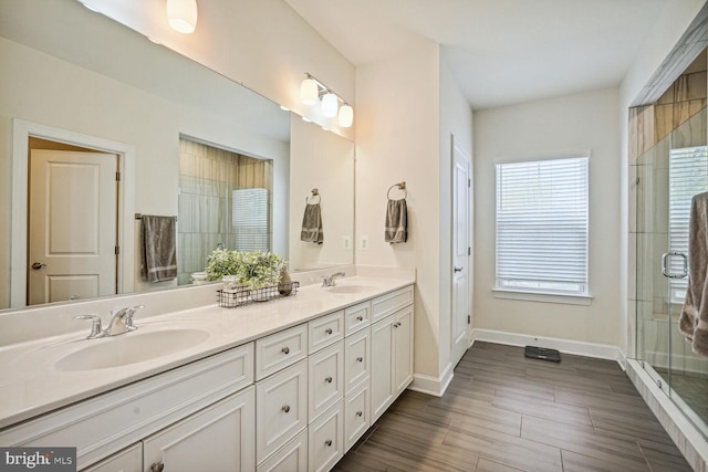 bathroom with a sink, baseboards, a shower stall, and double vanity
