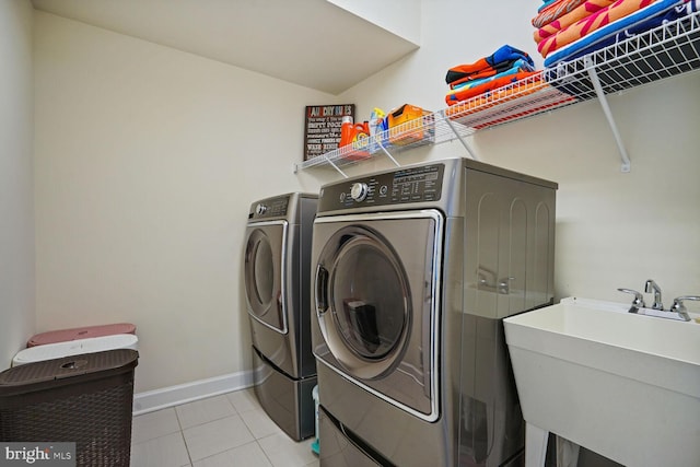 laundry room featuring laundry area, a sink, separate washer and dryer, baseboards, and light tile patterned floors