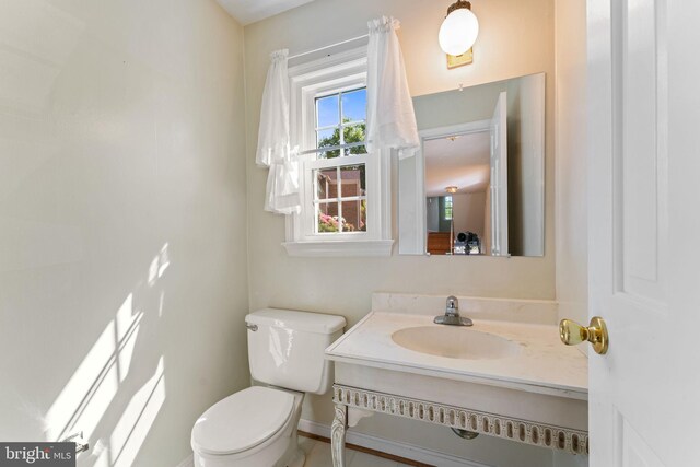 half bath with vanity, baseboards, and toilet