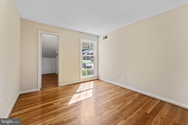 empty room featuring baseboards, light wood finished floors, and visible vents