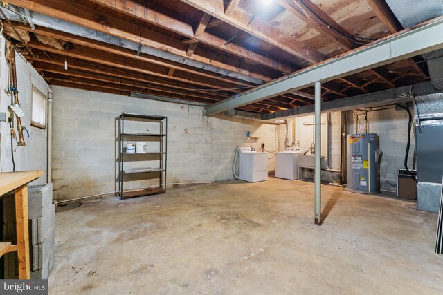 unfinished below grade area featuring washing machine and clothes dryer, a sink, and electric water heater