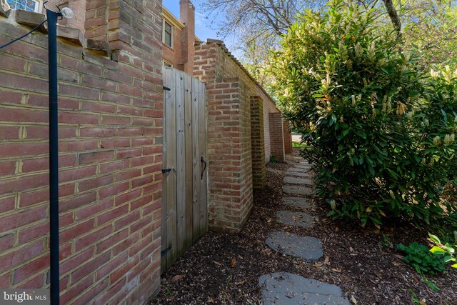 view of property exterior with brick siding and fence