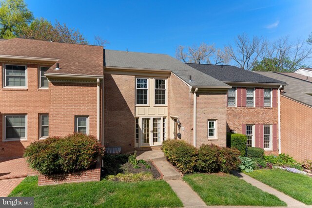 view of front of property featuring french doors, a front yard, and brick siding