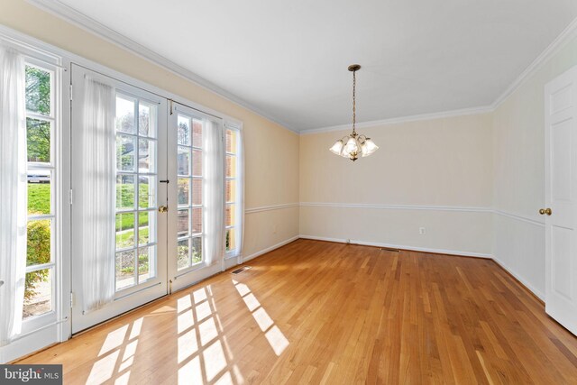 unfurnished dining area featuring plenty of natural light, ornamental molding, light wood-type flooring, and a chandelier