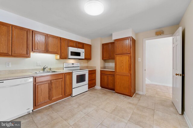 kitchen featuring a sink, brown cabinetry, and white appliances