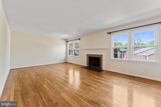unfurnished living room with a fireplace, baseboards, visible vents, and light wood-style floors