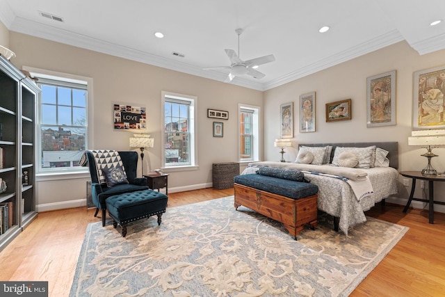 bedroom featuring light wood finished floors, multiple windows, ornamental molding, and visible vents