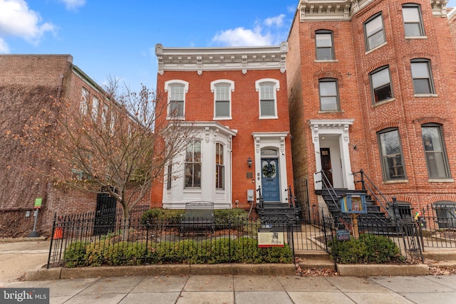 townhome / multi-family property with brick siding and a fenced front yard