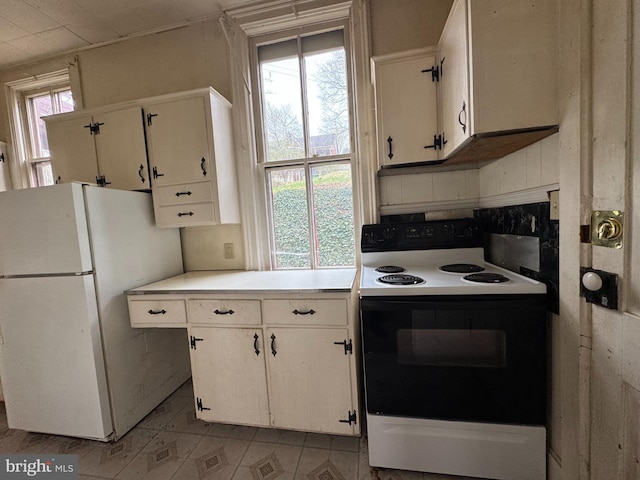 207 E Howard St, Bellefonte, PA 16823 - kitchen featuring white cabinets, range with electric stovetop, light countertops, and freestanding refrigerator