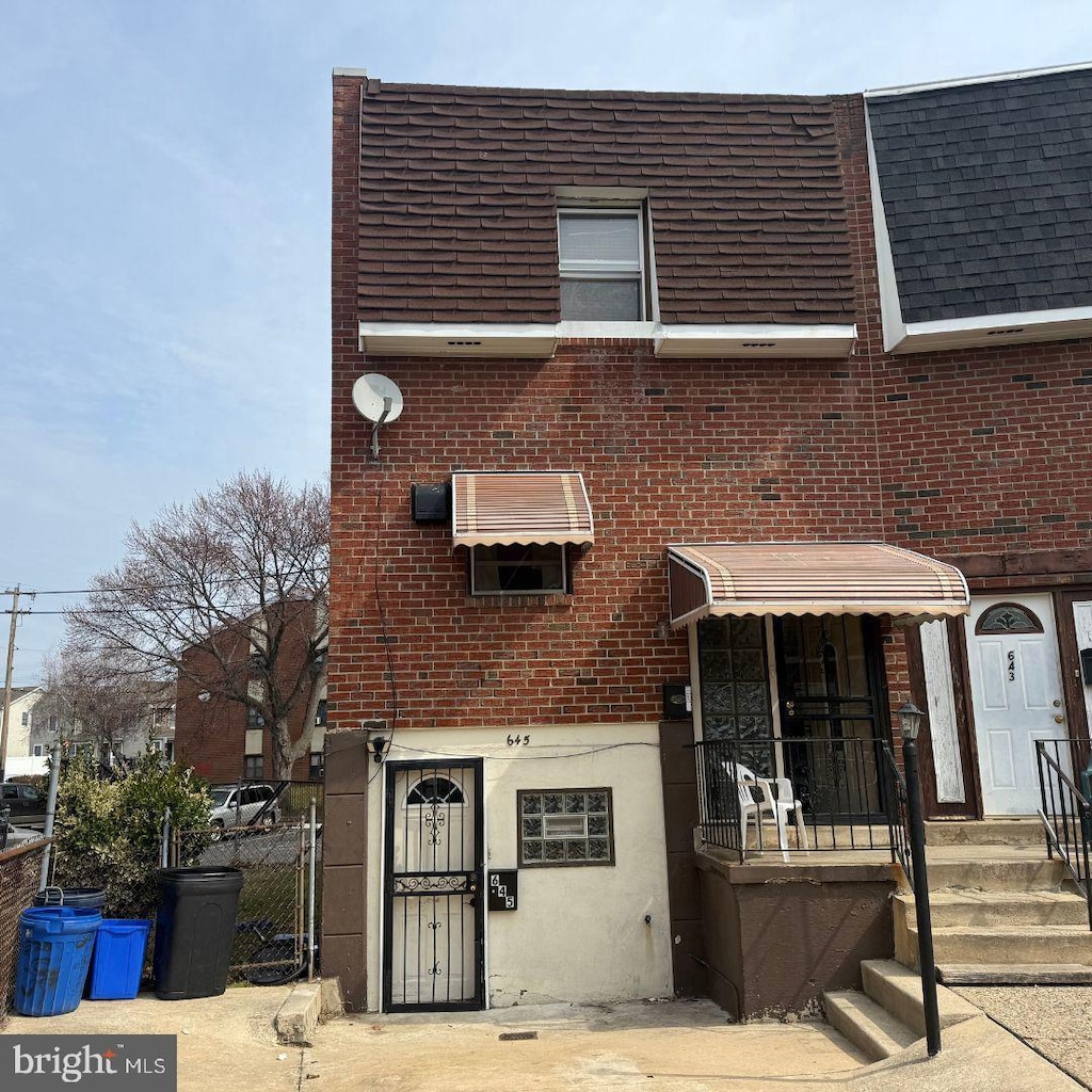 townhome / multi-family property featuring brick siding, fence, a gate, and roof with shingles