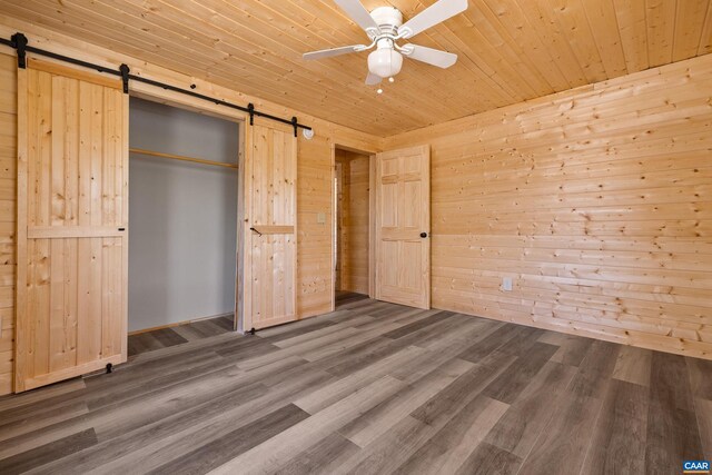 136 Wildwood Ln, Shenandoah, VA 22849 - unfurnished bedroom with wood finished floors, wood walls, and a barn door