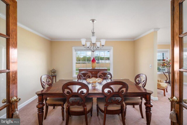 dining space featuring carpet flooring, baseboards, an inviting chandelier, and ornamental molding