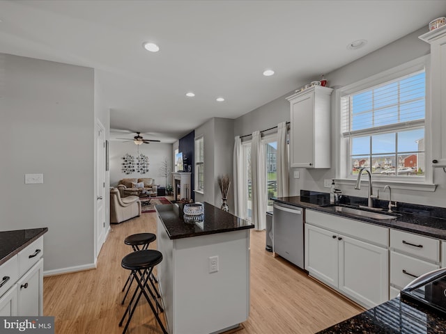 kitchen with open floor plan, a ceiling fan, light wood-style floors, dishwasher, and a sink