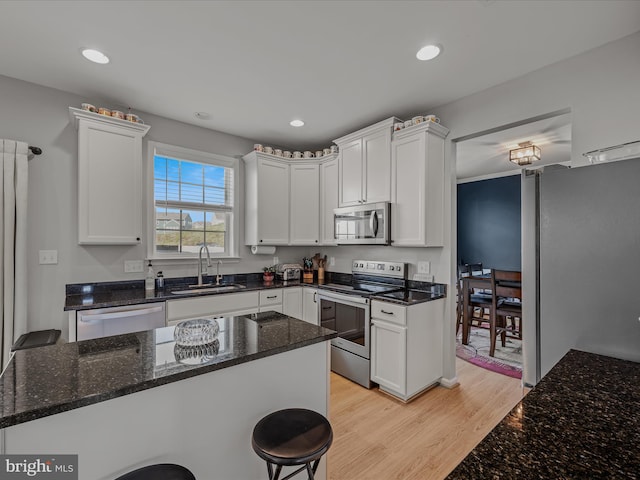 kitchen with a sink, white cabinets, appliances with stainless steel finishes, and dark stone countertops