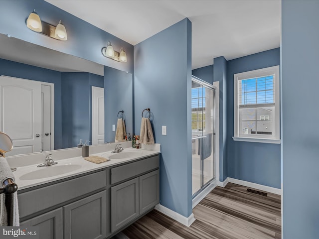 bathroom with a sink, visible vents, baseboards, and wood finished floors