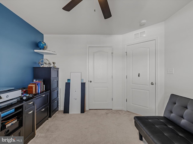 sitting room featuring light carpet, visible vents, and a ceiling fan