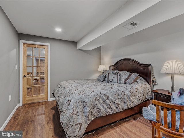 bedroom featuring visible vents, baseboards, and wood finished floors