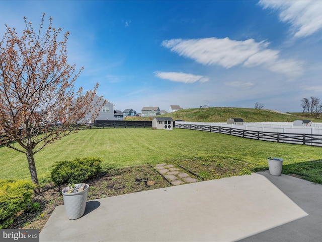 view of yard with an outbuilding, a fenced backyard, a storage shed, and a patio area