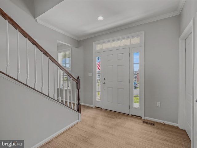 foyer entrance with light wood-style floors, stairs, visible vents, and ornamental molding