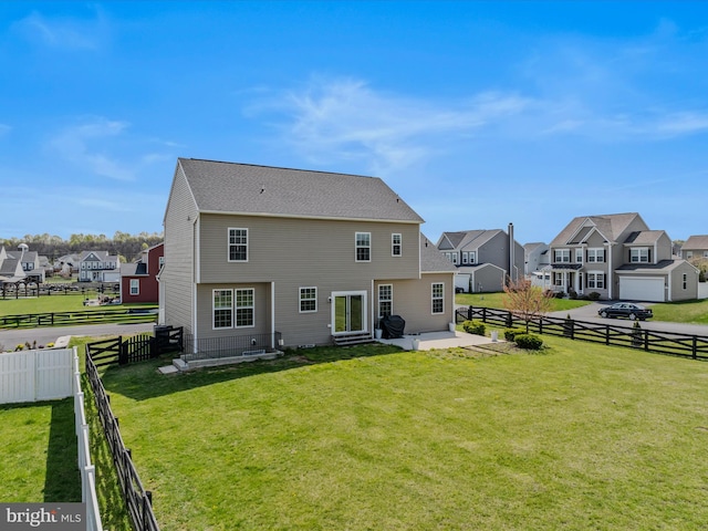 rear view of property featuring a yard, a fenced backyard, and a residential view