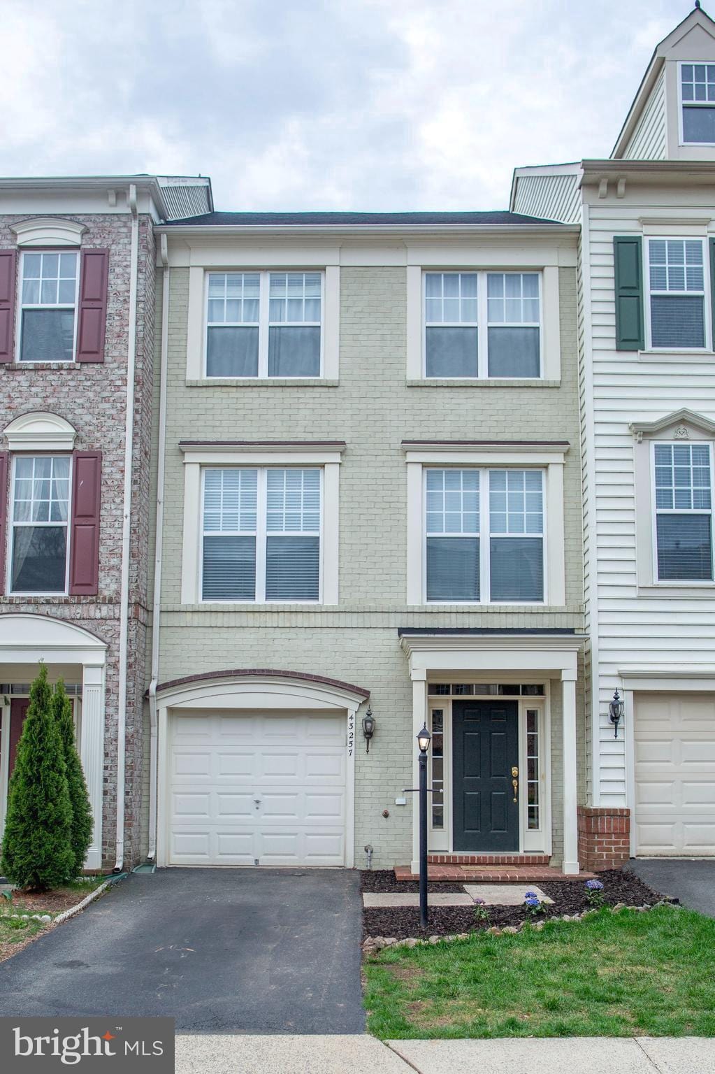 view of property with brick siding, an attached garage, and driveway