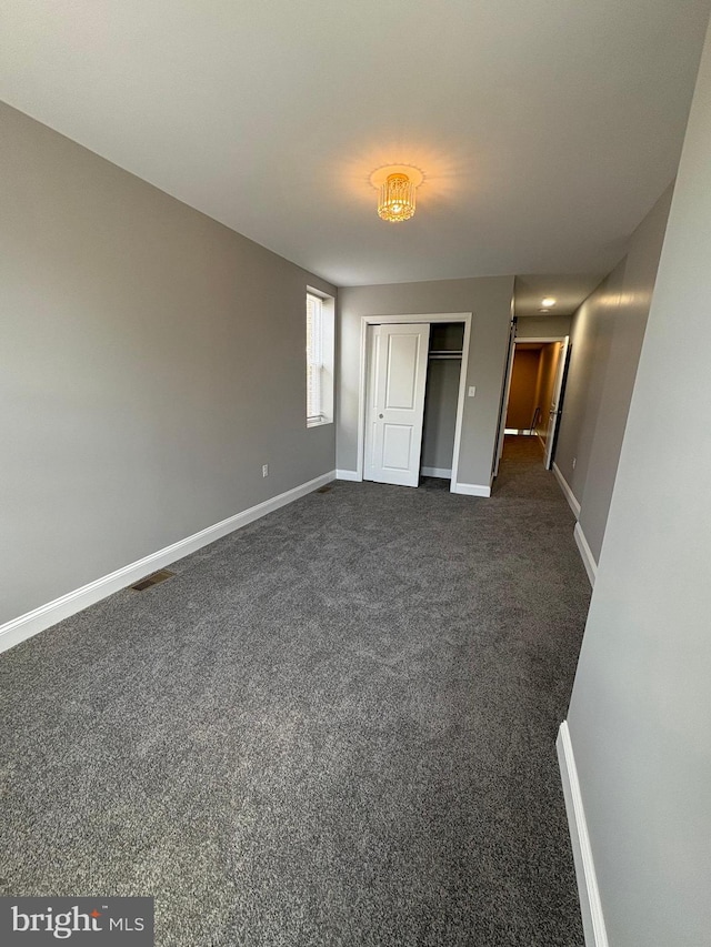 2241 E Preston St, Baltimore, MD 21213 - unfurnished bedroom featuring baseboards, dark colored carpet, and a closet