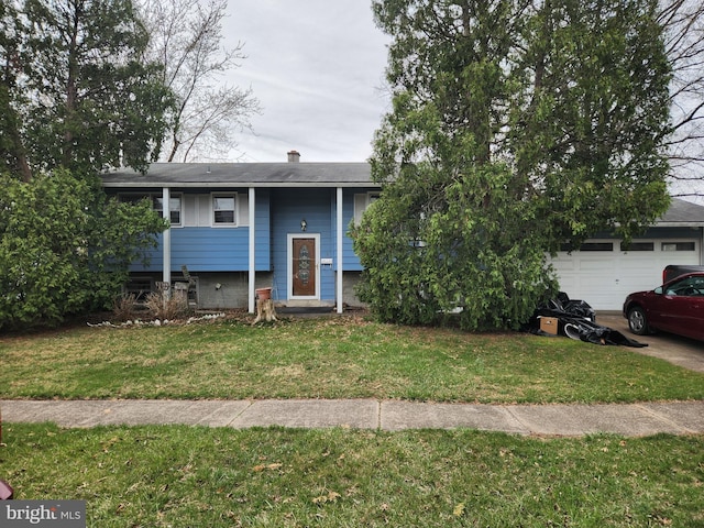 split foyer home featuring a garage, a chimney, and a front lawn