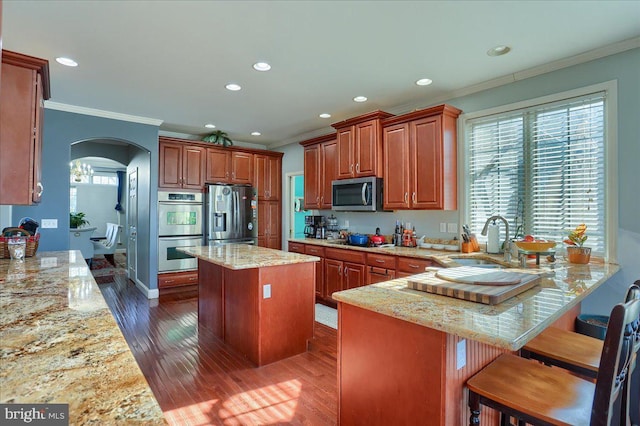 704 Goddard Dr, York, PA 17402 - kitchen with crown molding, arched walkways, light stone counters, a sink, and stainless steel appliances