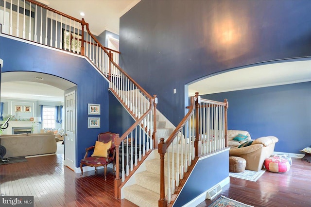 704 Goddard Dr, York, PA 17402 - stairs with baseboards, arched walkways, hardwood / wood-style flooring, a fireplace, and a towering ceiling