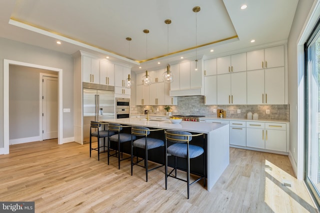 1127 Guilford Ct, Mclean, VA 22101 - kitchen with a tray ceiling, decorative backsplash, a kitchen bar, and stainless steel appliances