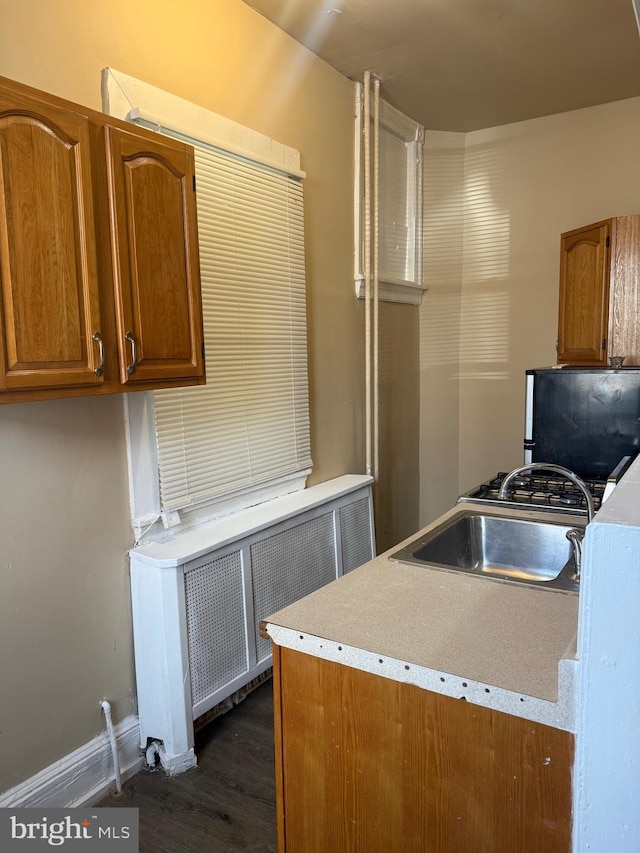 4561 N Camac St, Philadelphia, PA 19140 - kitchen with radiator, dark wood-style flooring, light countertops, a sink, and brown cabinets