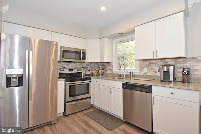 kitchen featuring a sink, light wood finished floors, white cabinetry, and stainless steel appliances