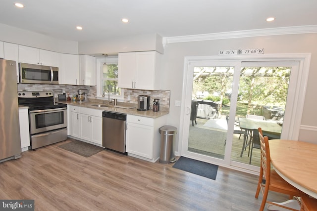 kitchen featuring stainless steel appliances, white cabinetry, a sink, and tasteful backsplash