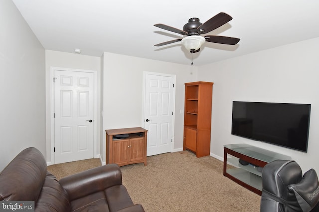living room with baseboards, ceiling fan, and light carpet