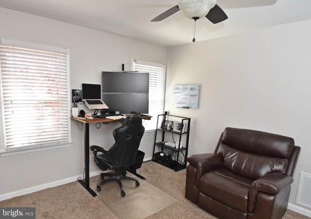 carpeted office space featuring baseboards, ceiling fan, and visible vents