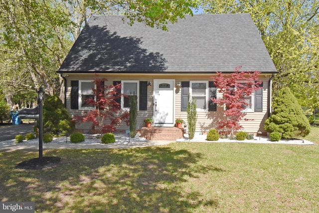 cape cod home with a shingled roof and a front yard