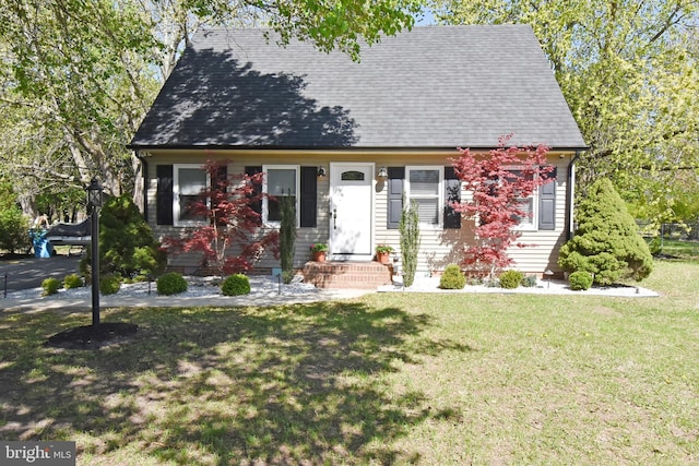 cape cod home with a shingled roof and a front lawn