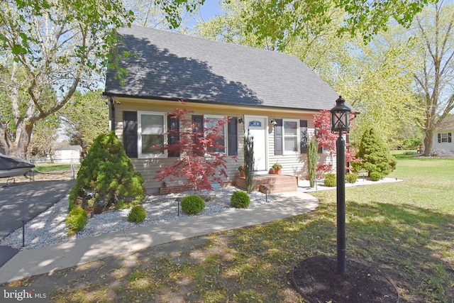 view of front of house with fence, a shingled roof, and a front lawn