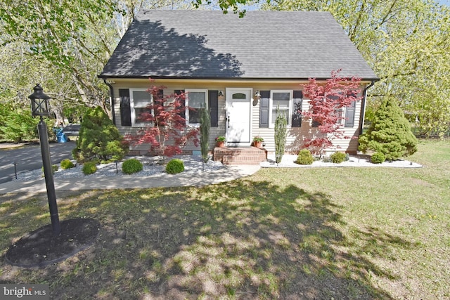 cape cod house with a shingled roof and a front yard